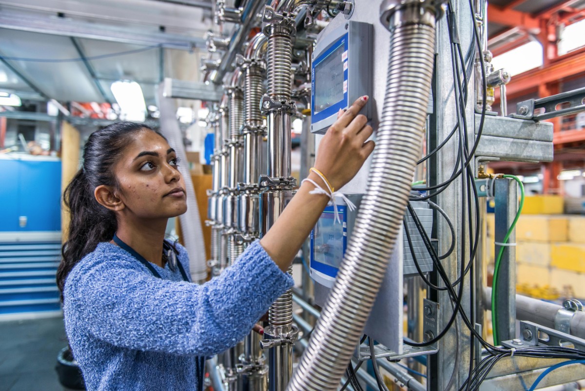 Student working with helium compressor at T­RIUMF.